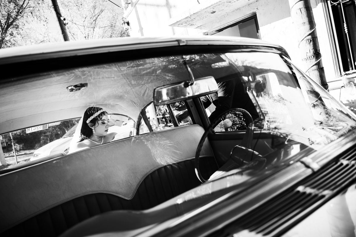Novia dentro de un auto clásico, en blanco y negro