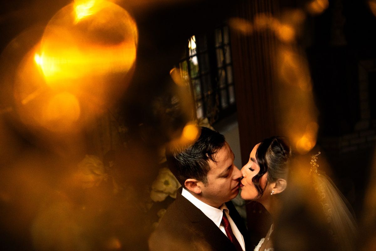 Novios besándose entre luces doradas