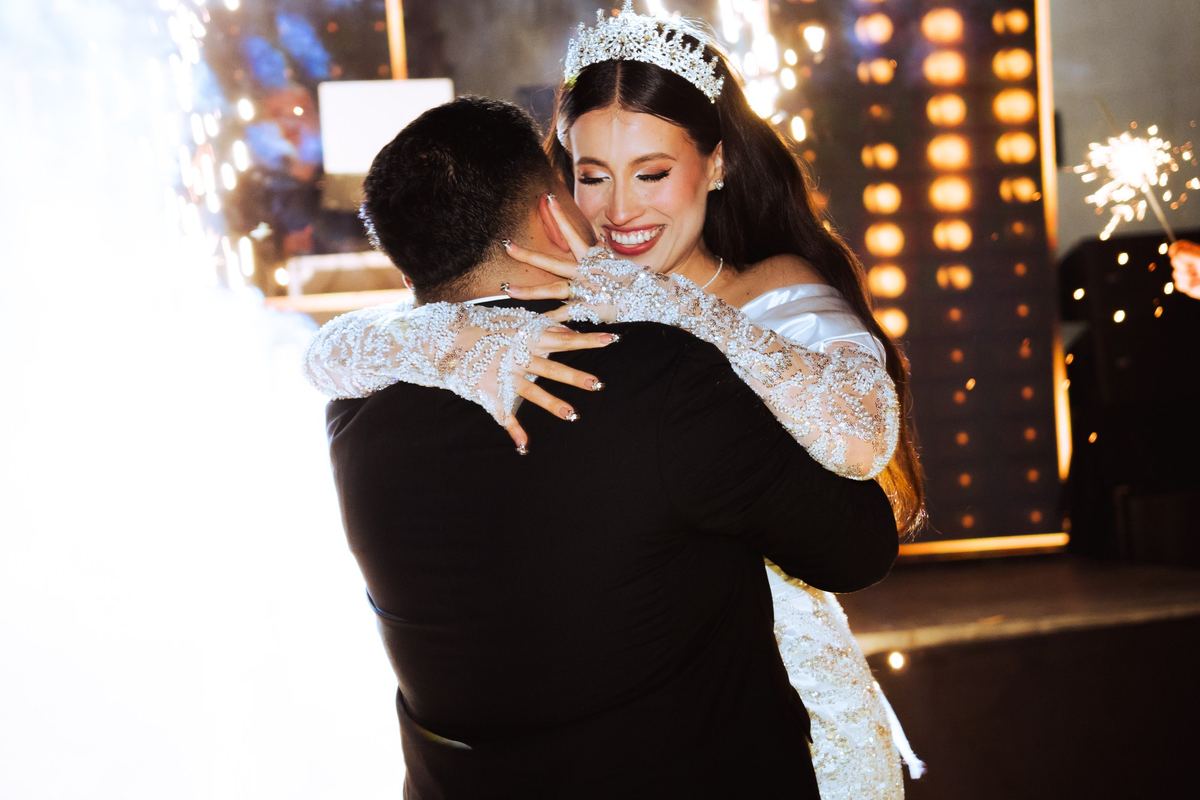 Novios abrazados con luces de bengala de fondo