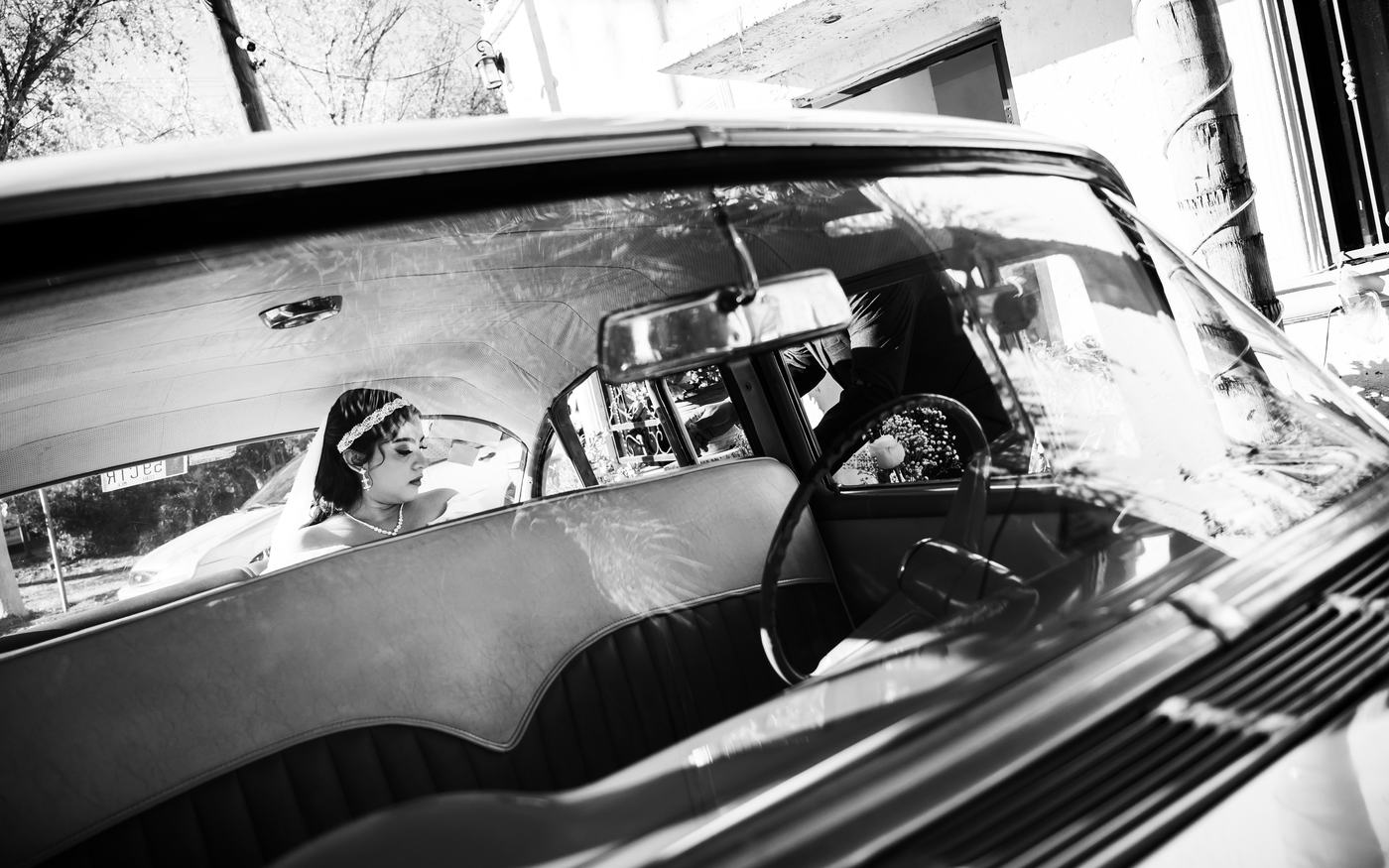Novia dentro de un auto clásico, en blanco y negro