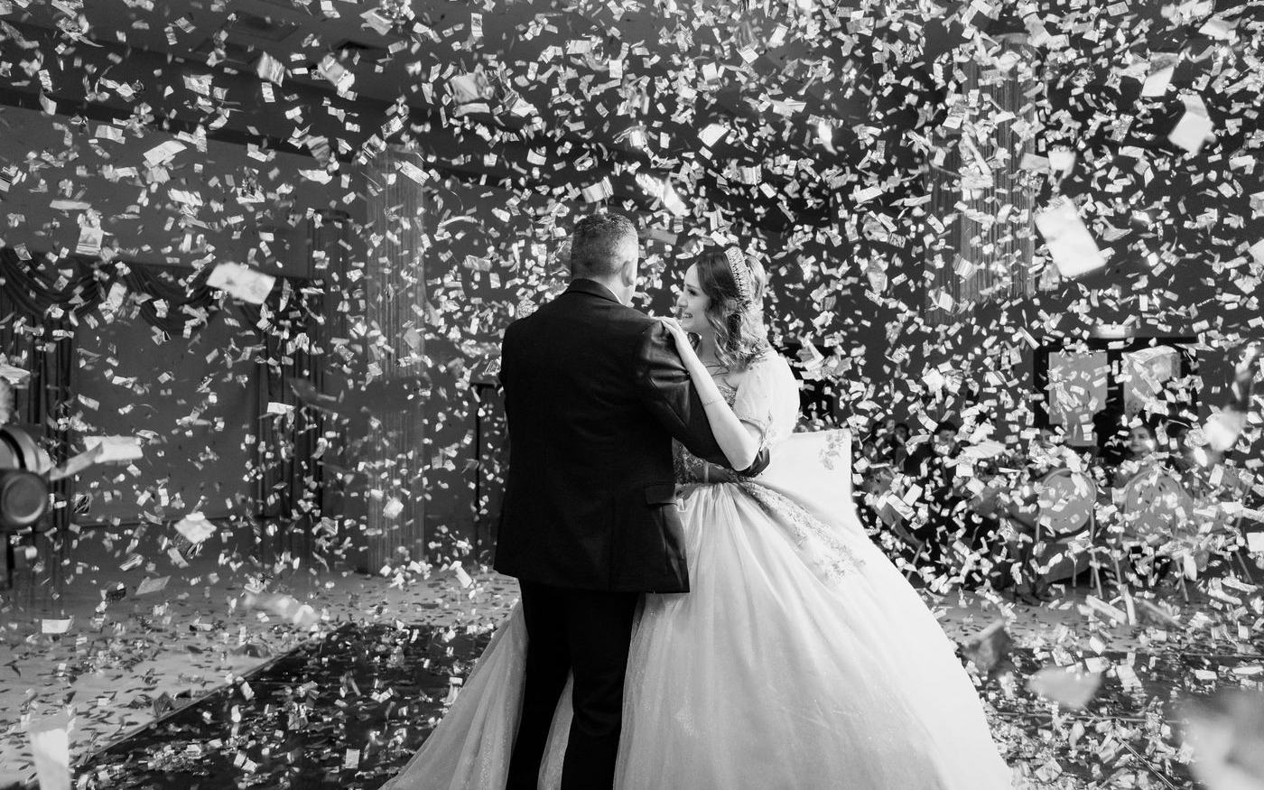 Quinceañera bailando el vals entre confeti, en blanco y negro