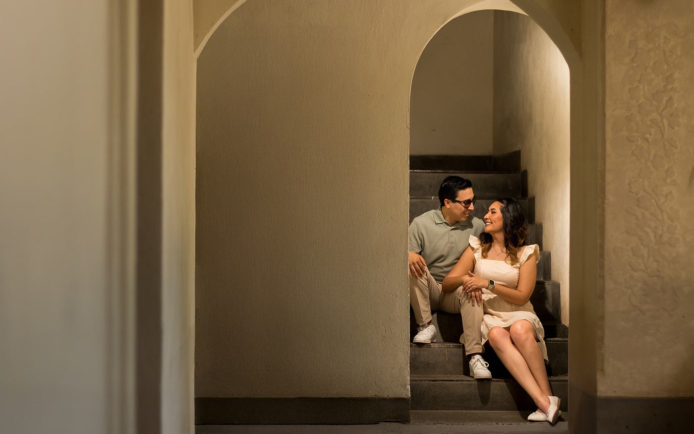 Pareja sentada en una escalera bajo arcos