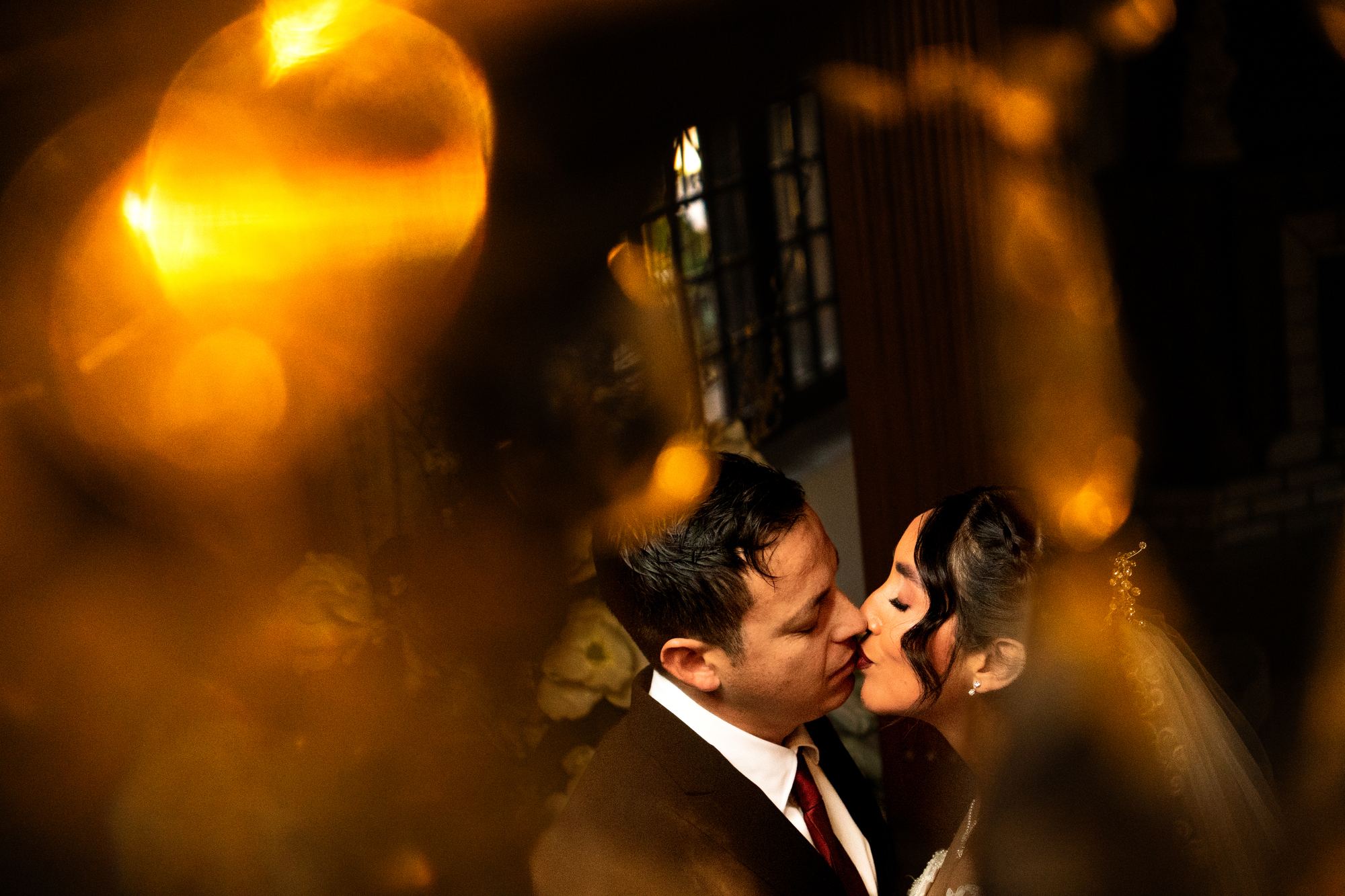 Novios a punto de besarse entre luces cálidas desenfocadas
