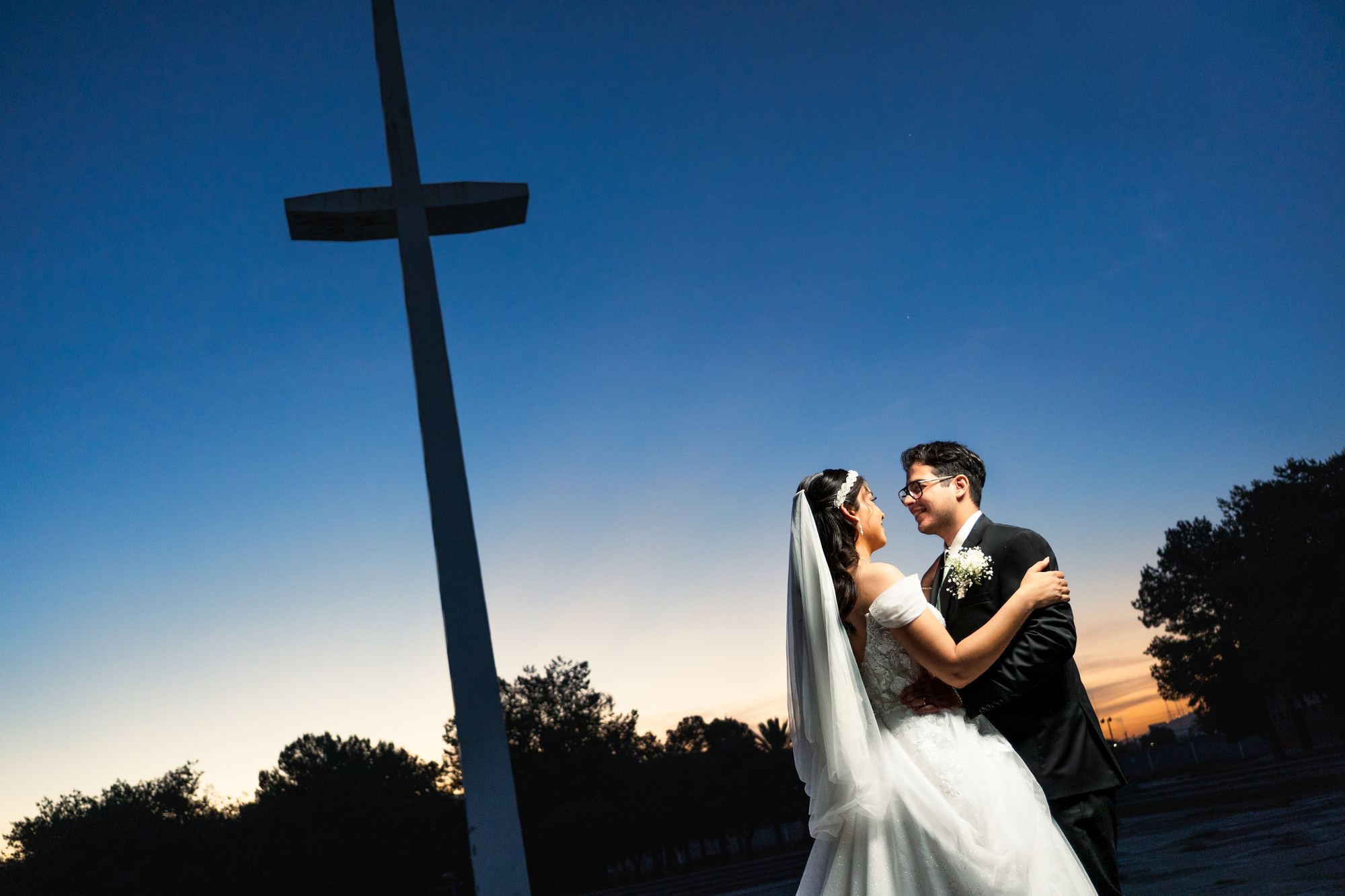 Novios abrazados al anochecer bajo el cielo azul