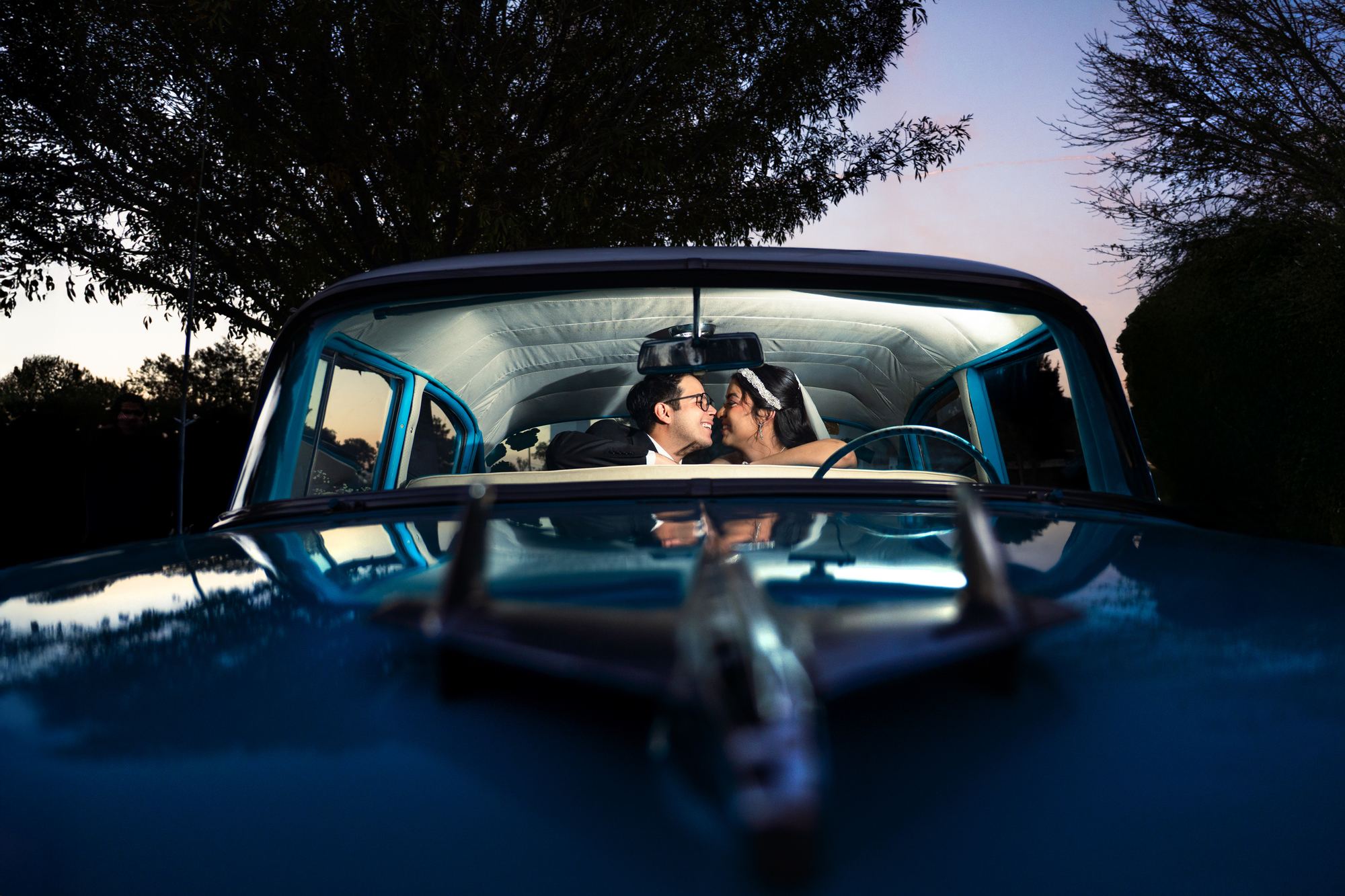Novios besándose dentro de un auto clásico azul
