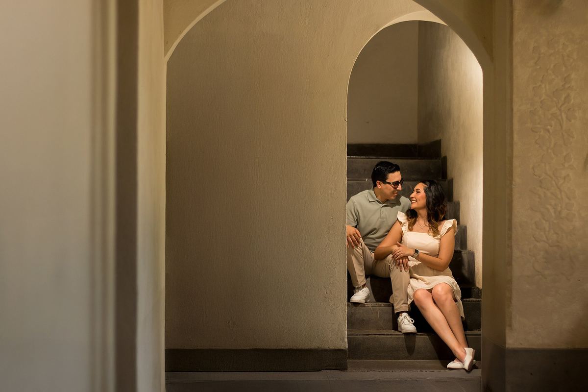 Pareja sentada en una escalera bajo arcos