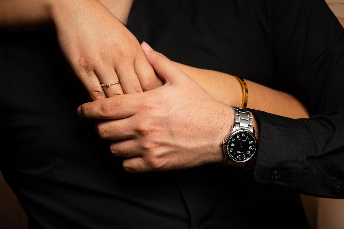 Manos entrelazadas con anillo de compromiso y reloj