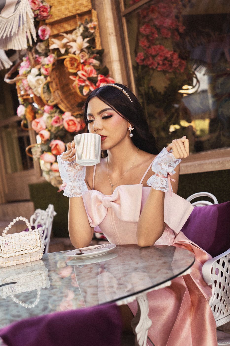 Quinceañera con vestido rosa tomando café en una mesa con flores
