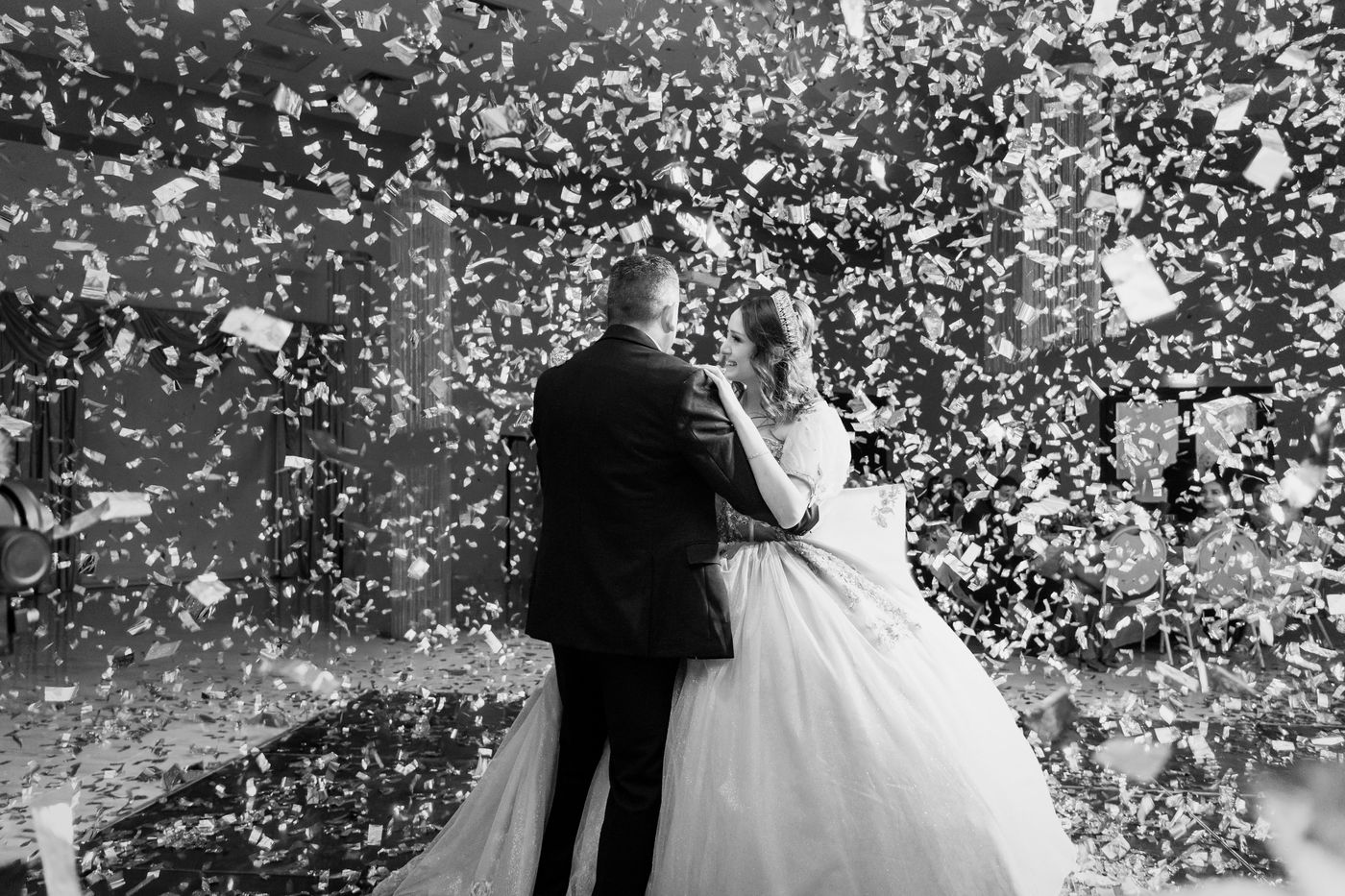 Quinceañera bailando el vals entre confeti, en blanco y negro