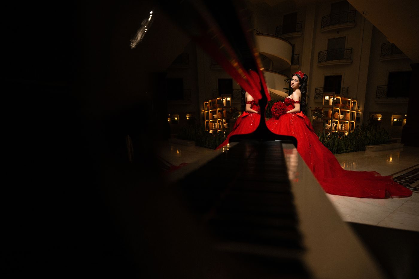 Quinceañera con vestido rojo reflejada en un piano